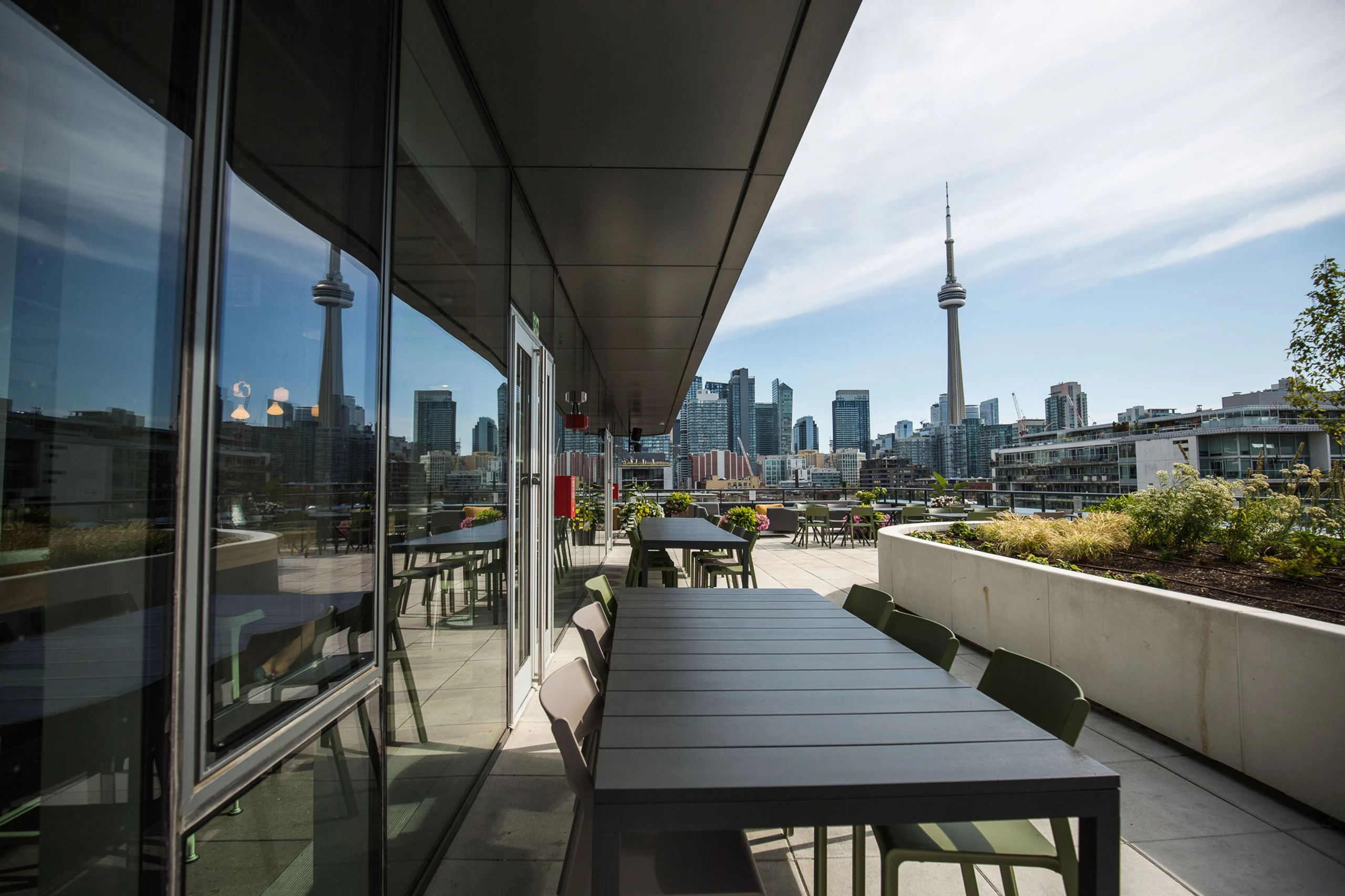 Rooftop terrace with outdoor dining tables and CN Tower views