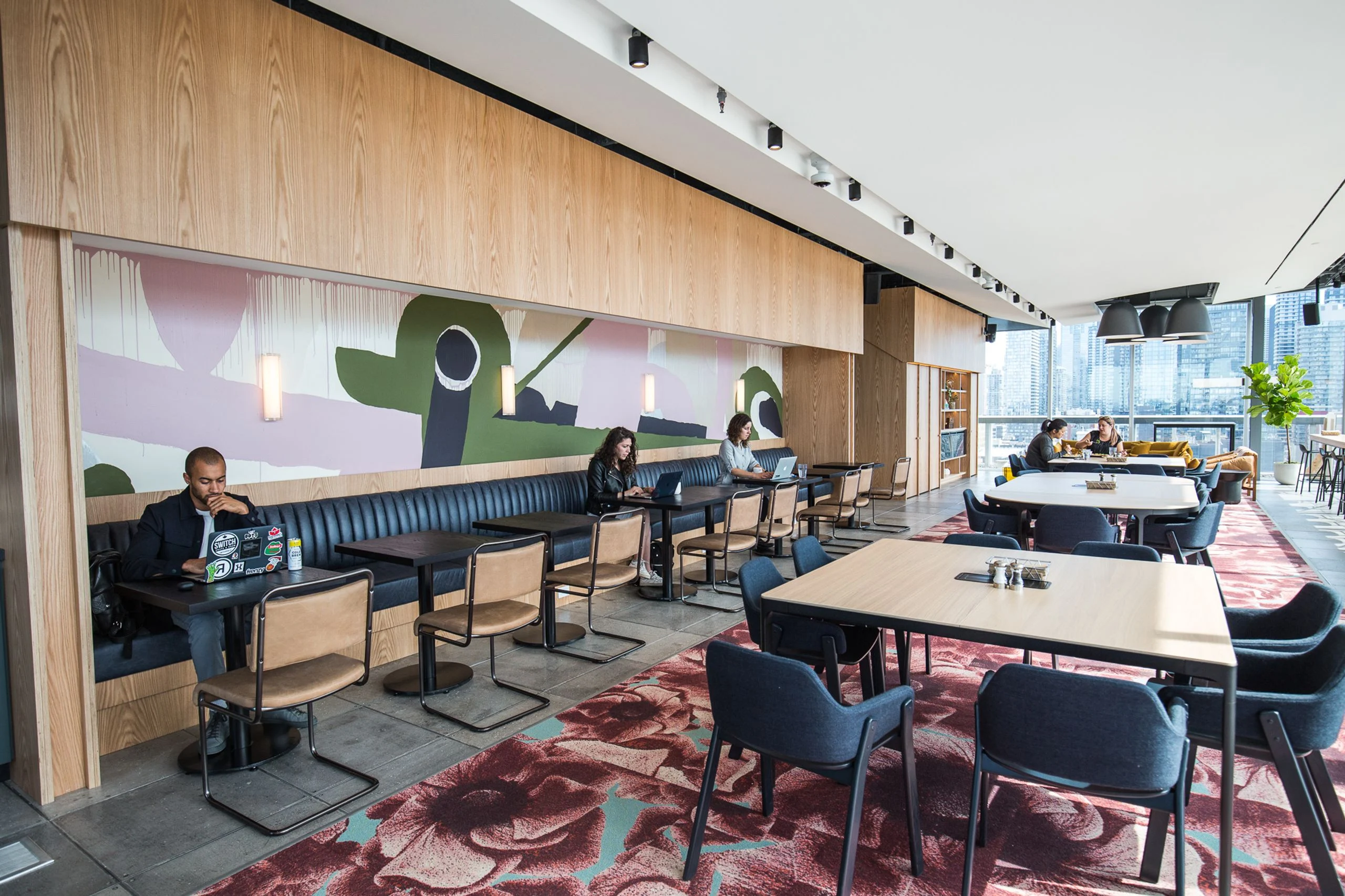 Cafeteria and social dining with an oak banquette, floral rug, mural and skyline views