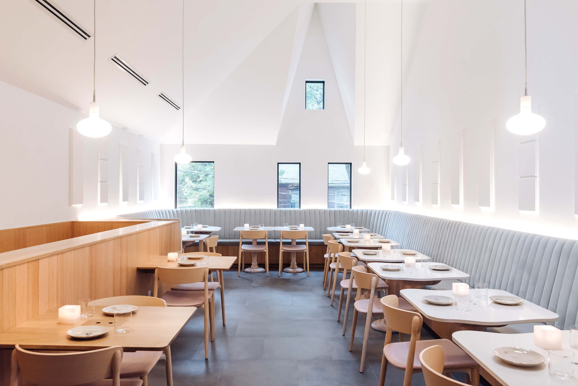 Sara restaurant dining room by The Food Dudes — minimalist white interior with banquette seating and vaulted ceiling